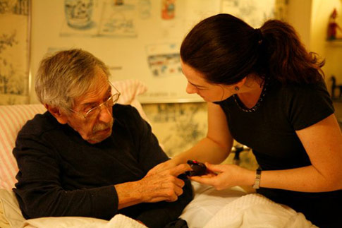 Home care nurse taking care of elderly man in bed