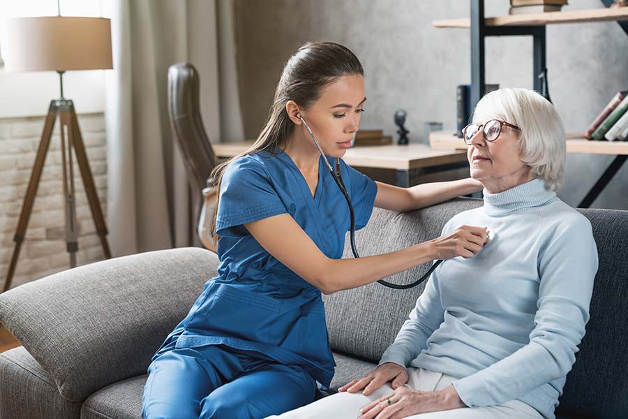 Nurse listening to a senior woman's heart